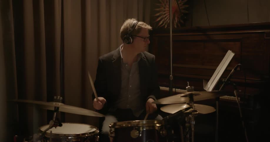 A man plays the drums with headphones on