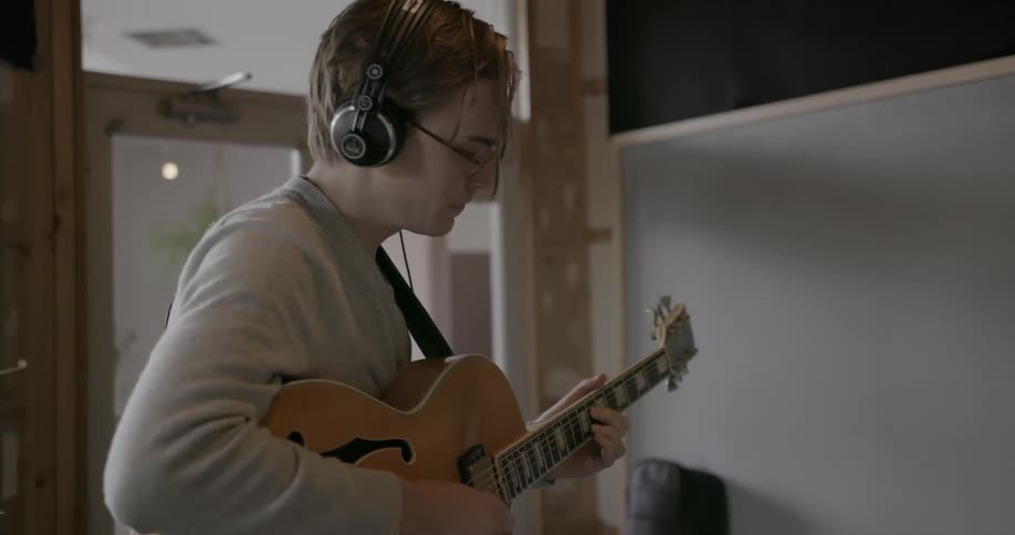 Man stands in studio playing electric guitar