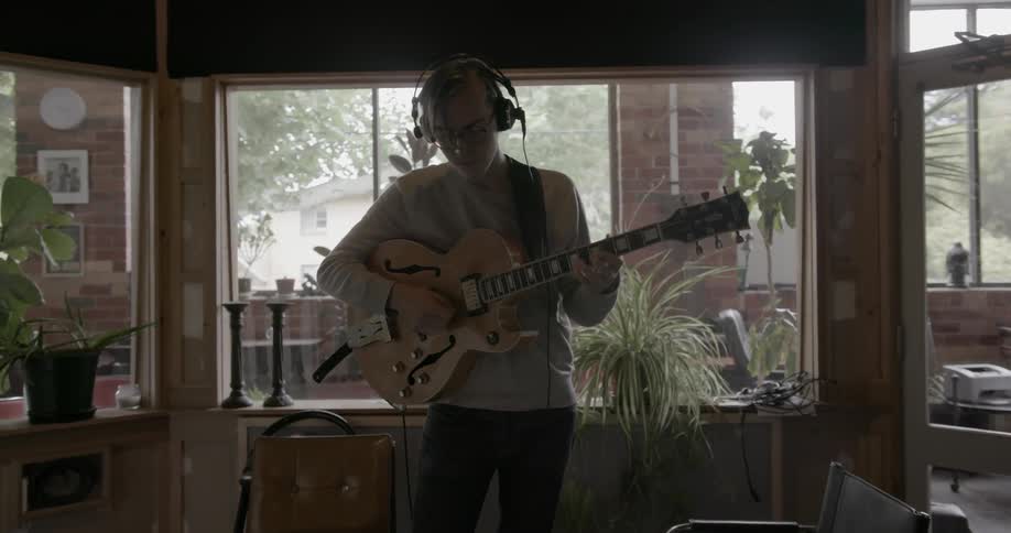 Man stands in studio playing electric guitar