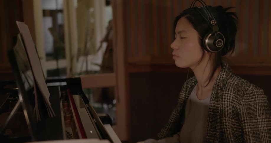 A woman is playing a piano in a music recording studio