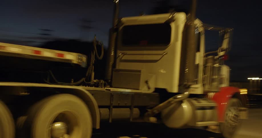 A truck drives next to train tracks at night