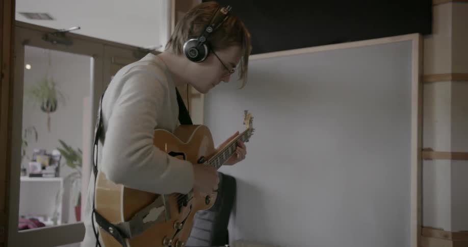 Man plays guitar while wearing headphones
