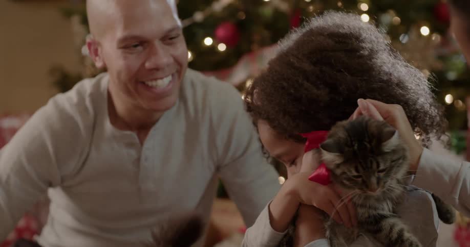 A dad smiles as his daughter hugs the cat she got as a christmas present