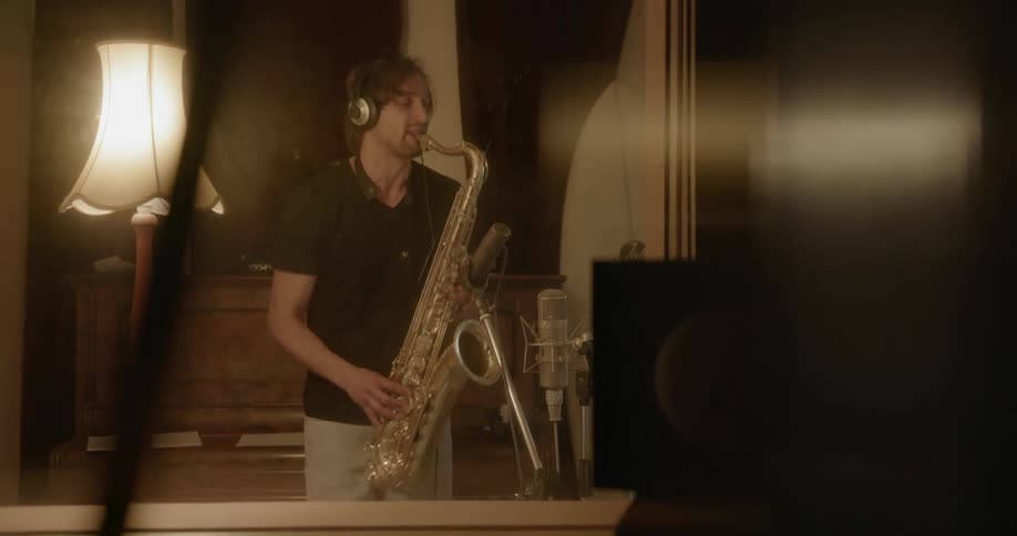 Man plays a saxophone and stops to lean over