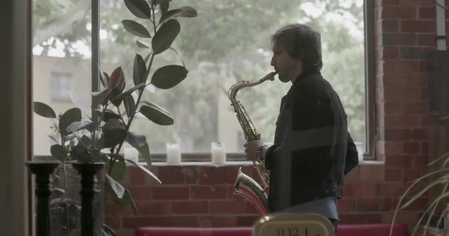 A man playing the saxophone is visible through a window