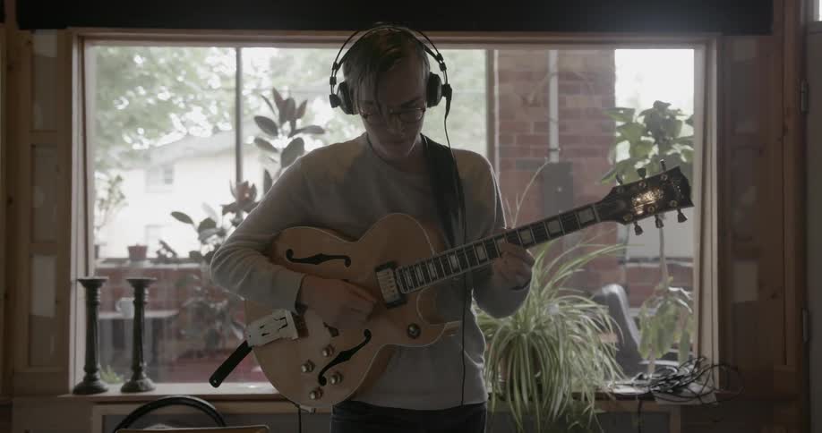 A man plays guitar in a music studio