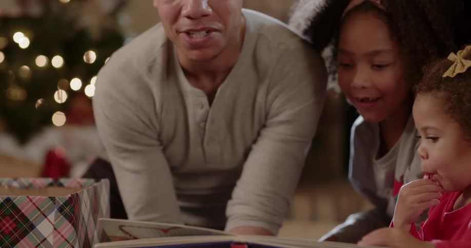 People sit around a christmas tree and open presents