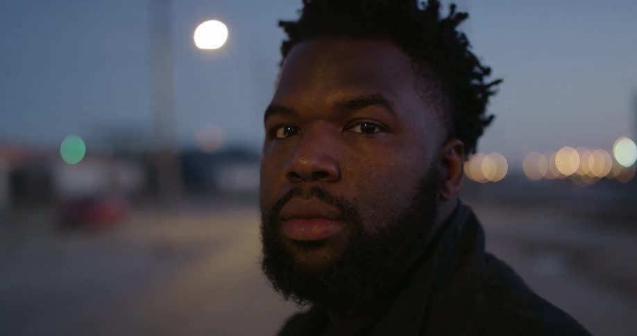 A man stands on a city street at night