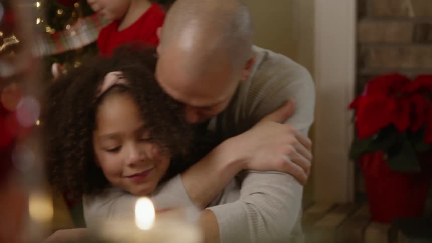 A man is hugging his daughter on christmas morning