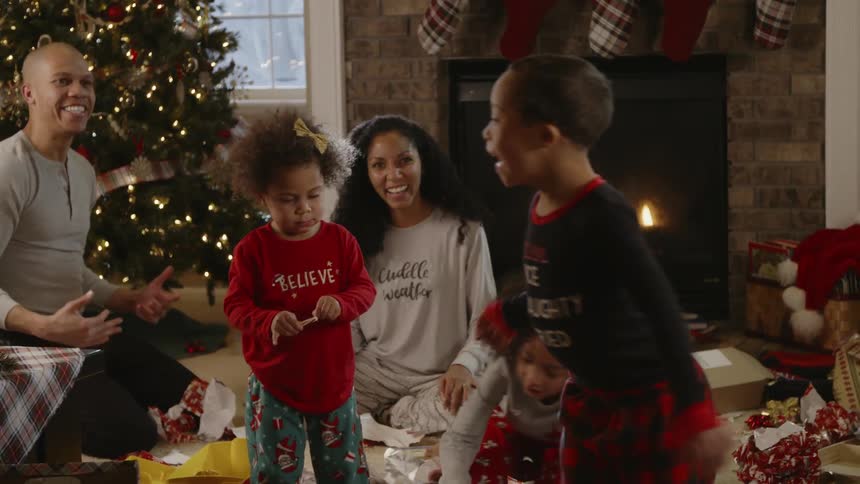 People sit around a christmas tree and open presents