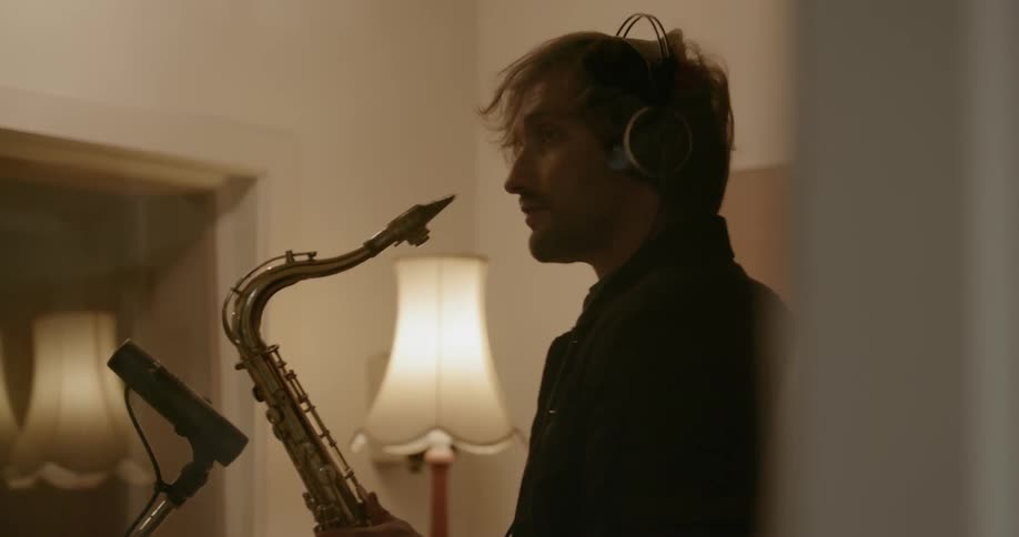 A man plays a saxophone in a recording studio