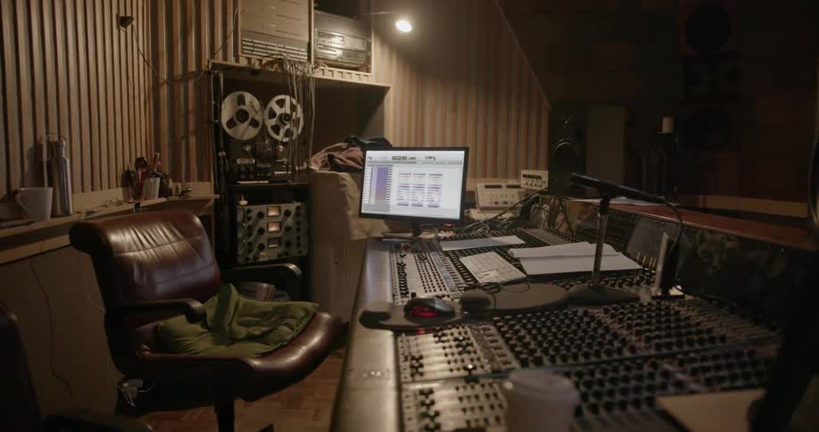 An empty chair behind music recording and mixing equipment