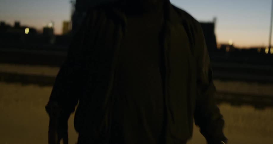 Man walks outside at dusk, scratching head and wiping face