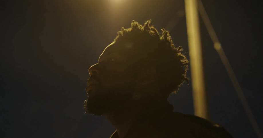 Man stands under street lamp at night