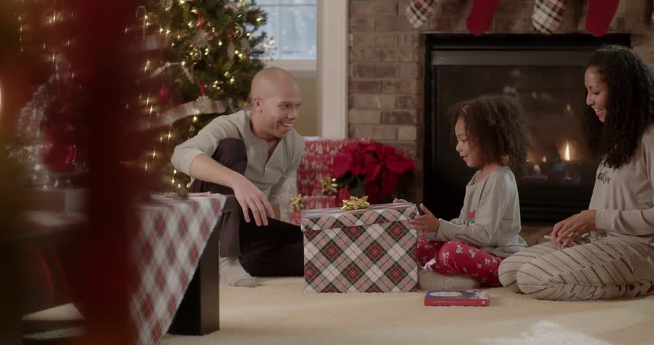 People sit around a christmas tree and open presents