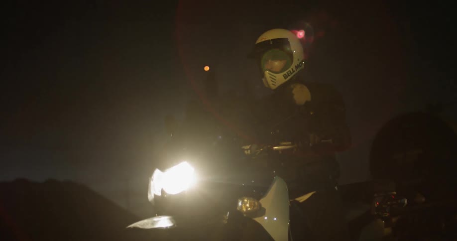 Motorcyclist waits on cycle at night
