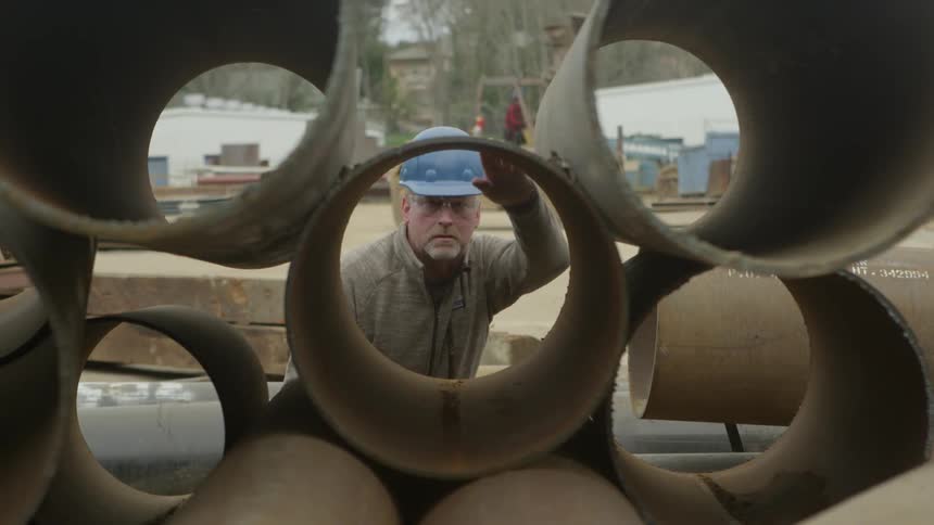 Construction worker measures some large tubes