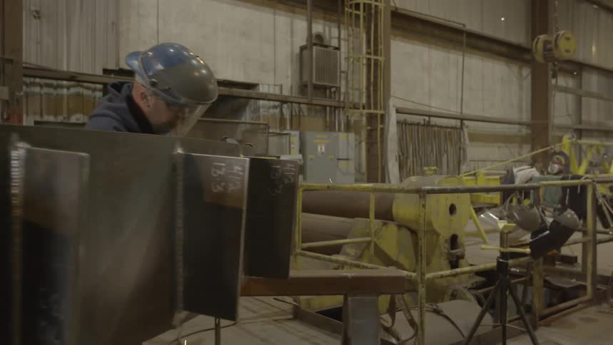 A white man works inside a factory
