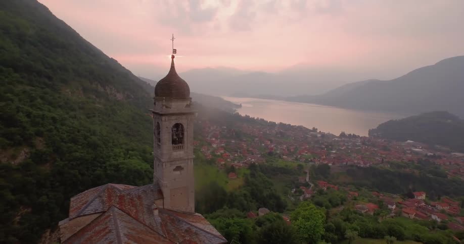 A church sits on a hill overlooking a village at sunset