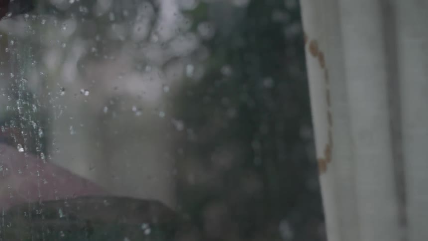 Raindrops hit the outside of a window