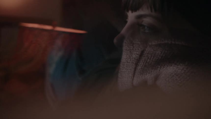 A woman sits in a dark room