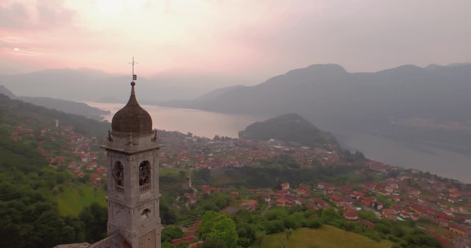Looking past a steeple down at the countryside and homes below at sunset