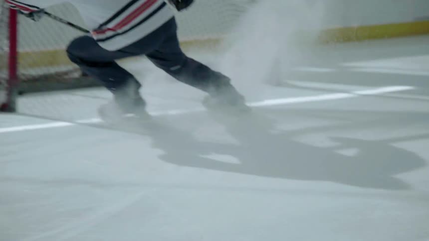Hockey player skates at stops in front of the net