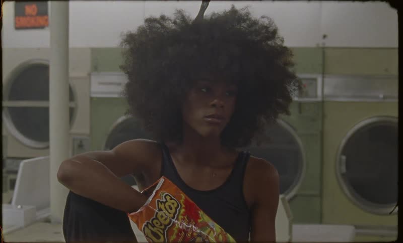 A woman eats cheetos in a laundromat