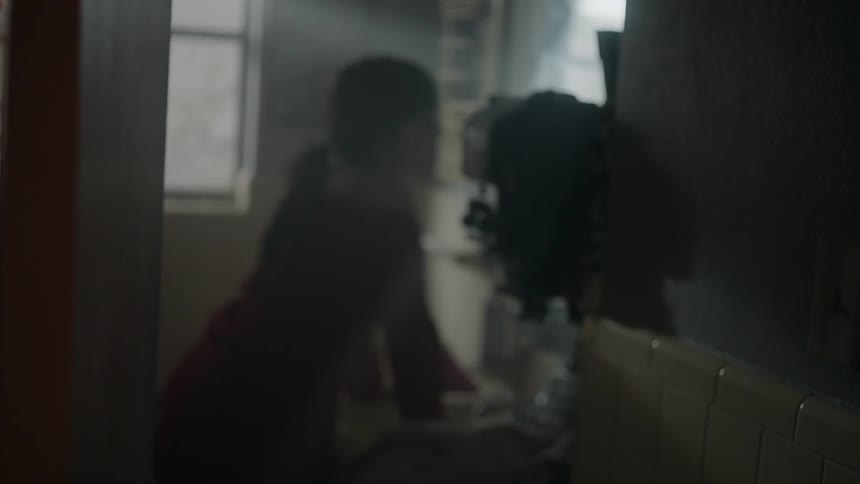 Woman looks into a mirror in a dim bathroom