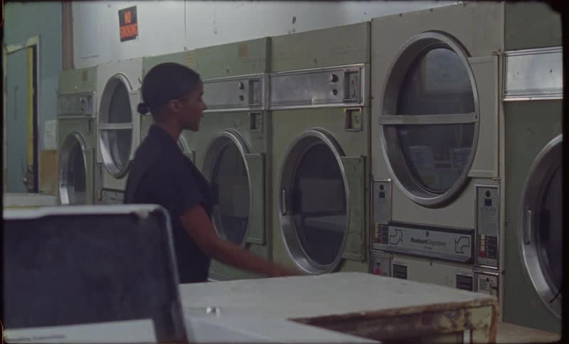 A woman points at a dryer in a laundromat