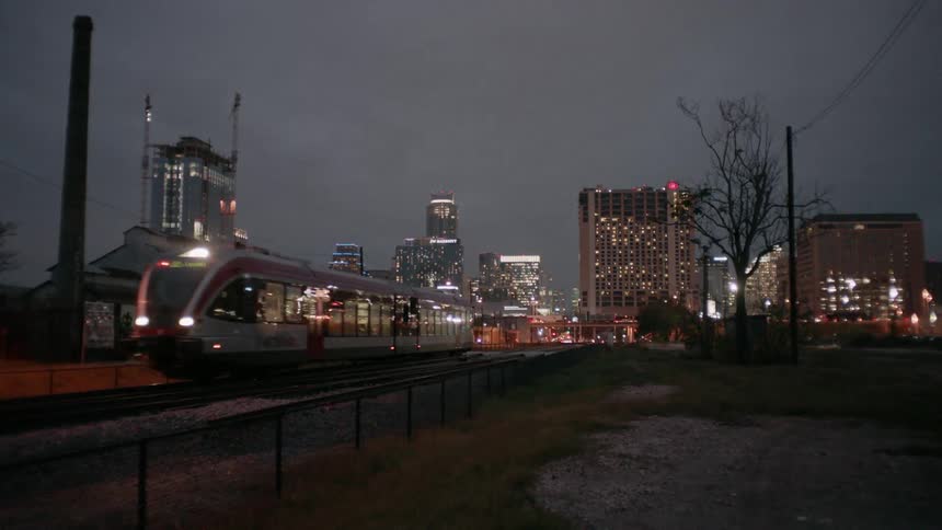 Train leaving a station in a city at night