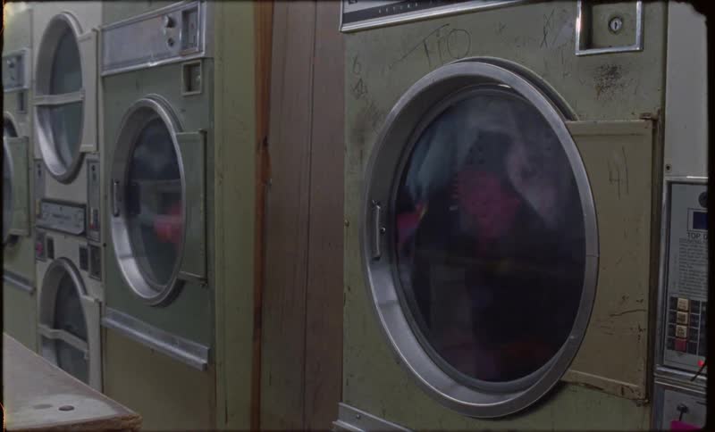 Clothes are spinning in dryers in a laundromat at night
