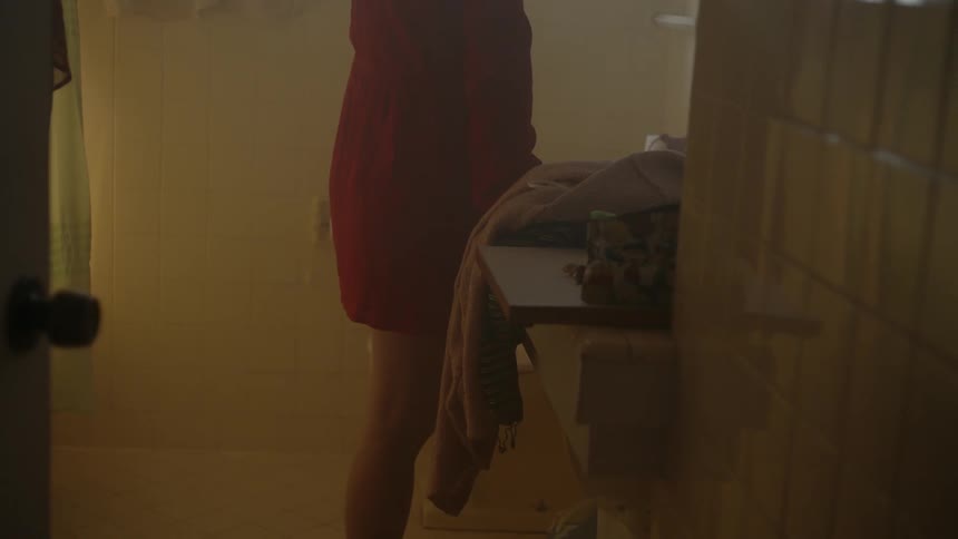 A woman is standing in a bathroom leaning on a counter