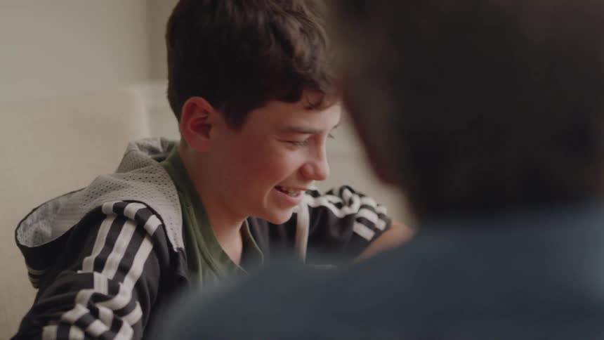 Child smiles and talks to the person sitting next to him