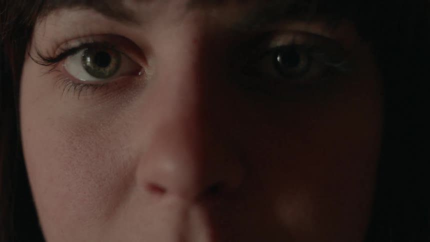 A close up of a woman with green eyes and red lipstick on her lips