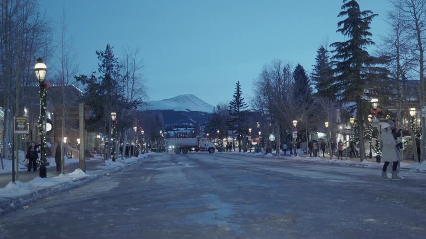 A busy snowy street with a mountain in the distance at sunset