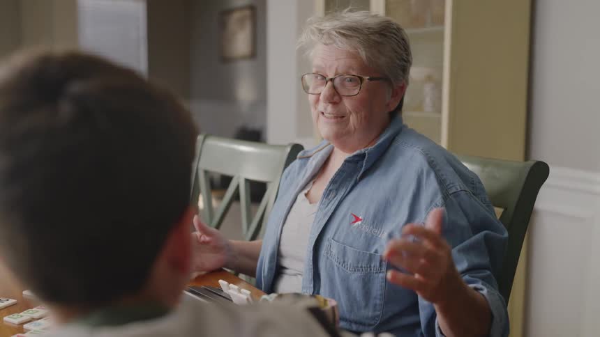 An older woman and a boy are playing a game at a table during the day