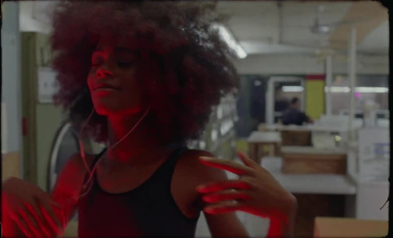Woman wearing earbuds dances in a laundromat at night