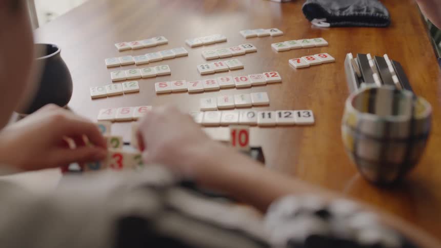 A woman and boy play a game at a dining room table