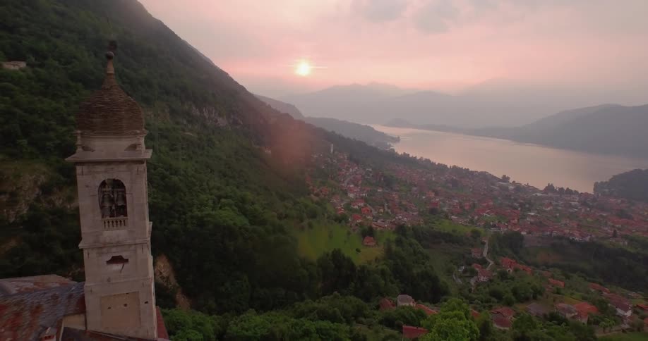 The sun is sitting over a town next to a mountain