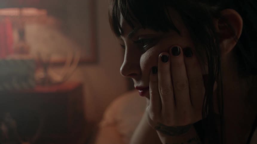 Woman sits with hand on her cheek