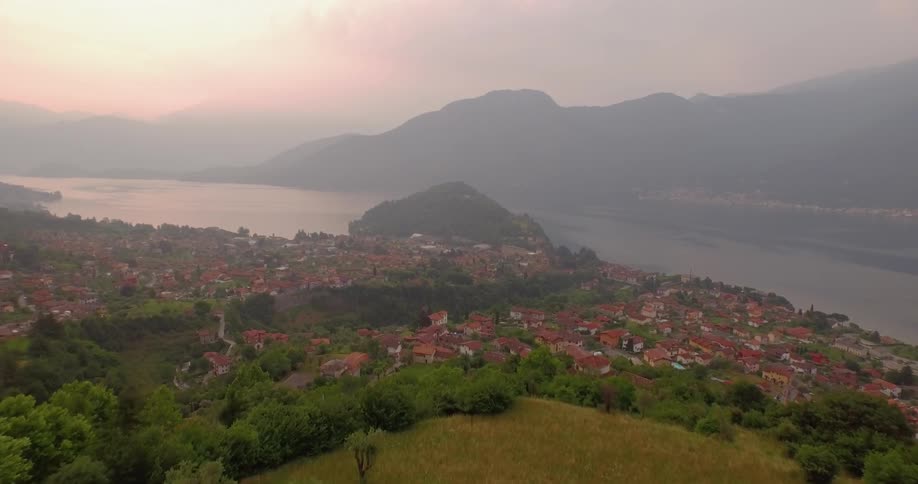 The sun sets over a mountain lake and town