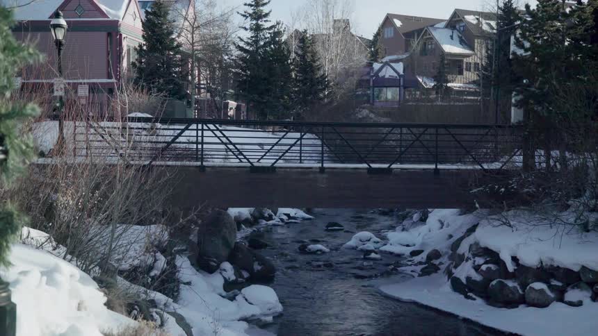 A river is trickling beneath a bridge in an alpine village in winter