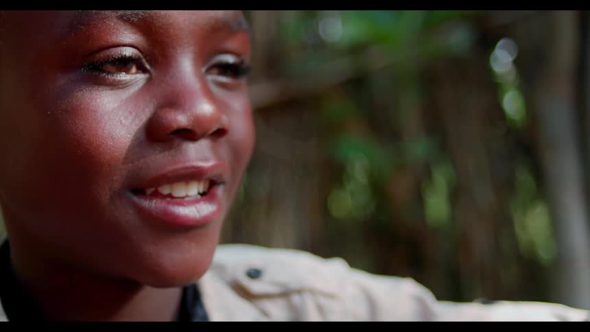 Child's face smiling outside near trees