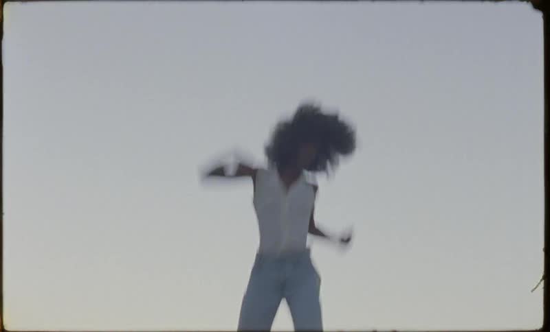 A woman is bouncing on a trampoline outside at dusk