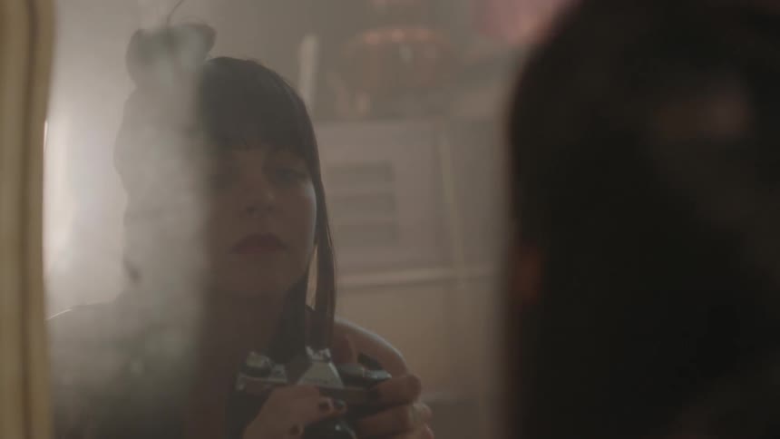 A woman takes a photograph of her reflection in a mirror