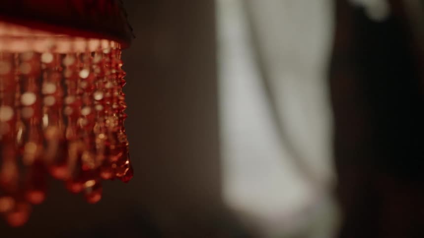 A woman stands near a beaded lamp
