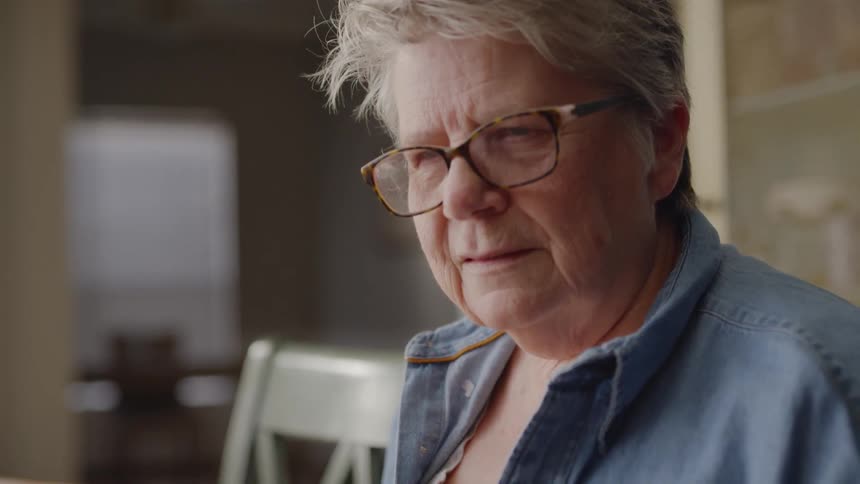 An older woman is talking to someone inside during the day