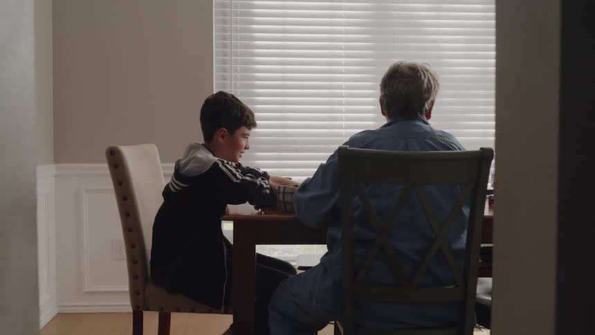 An older woman and a bar a playing a game at a table indoors in daylight