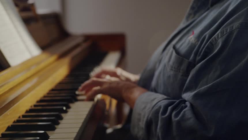A woman wearing glasses plays the piano